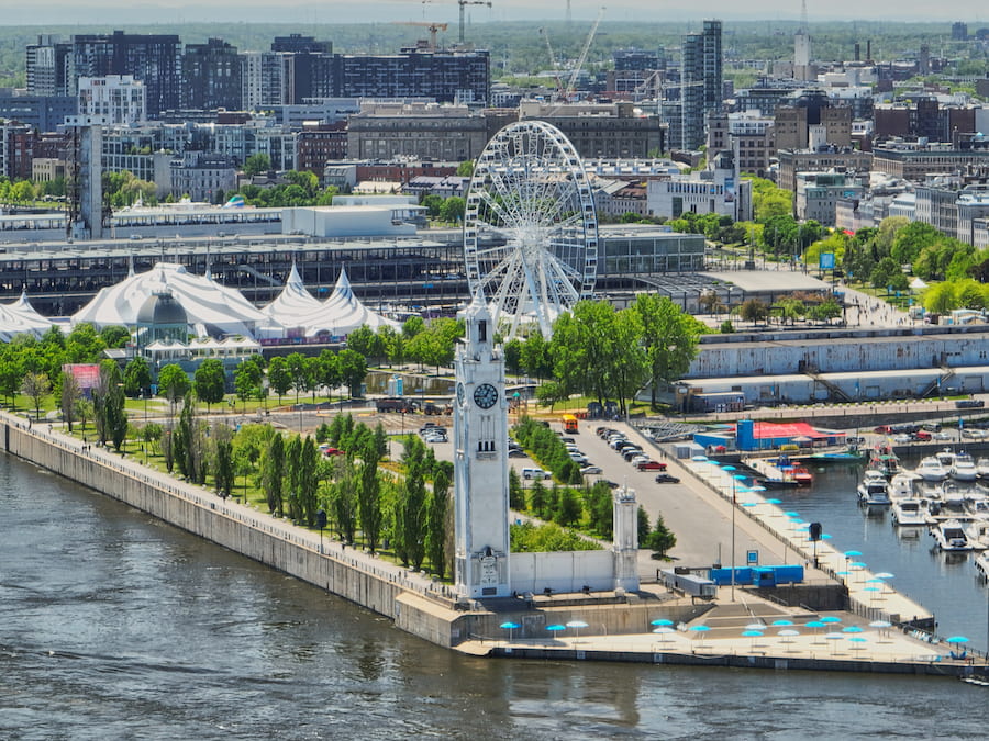 Aerial view of the Old Port of Montreal featuring the Clock Tower, the La Grande Roue Ferris wheel, and the city skyline in the background