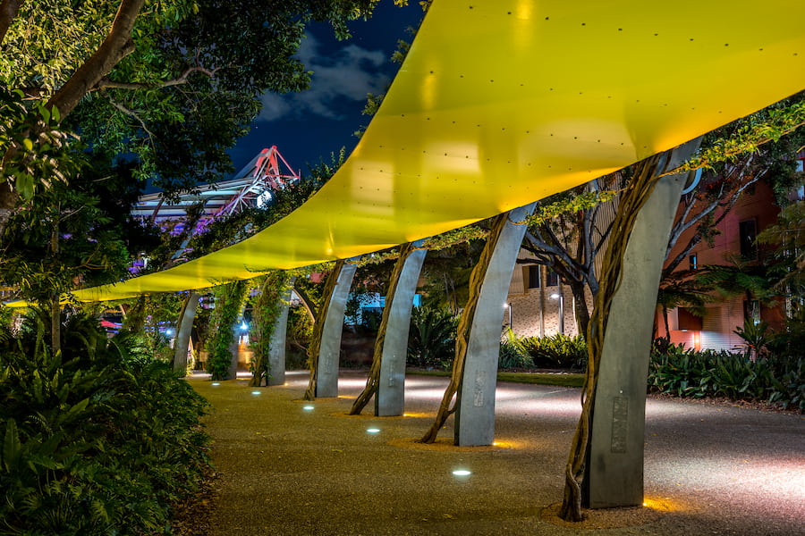 Walkway with vine-covered pillars at night in the South Bank Parklands of Brisbane.